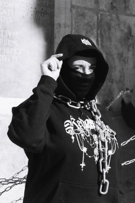 Primer plano modelo morgue planet con cadena enrollada al cuello y sudadera con capucha blanca y negra