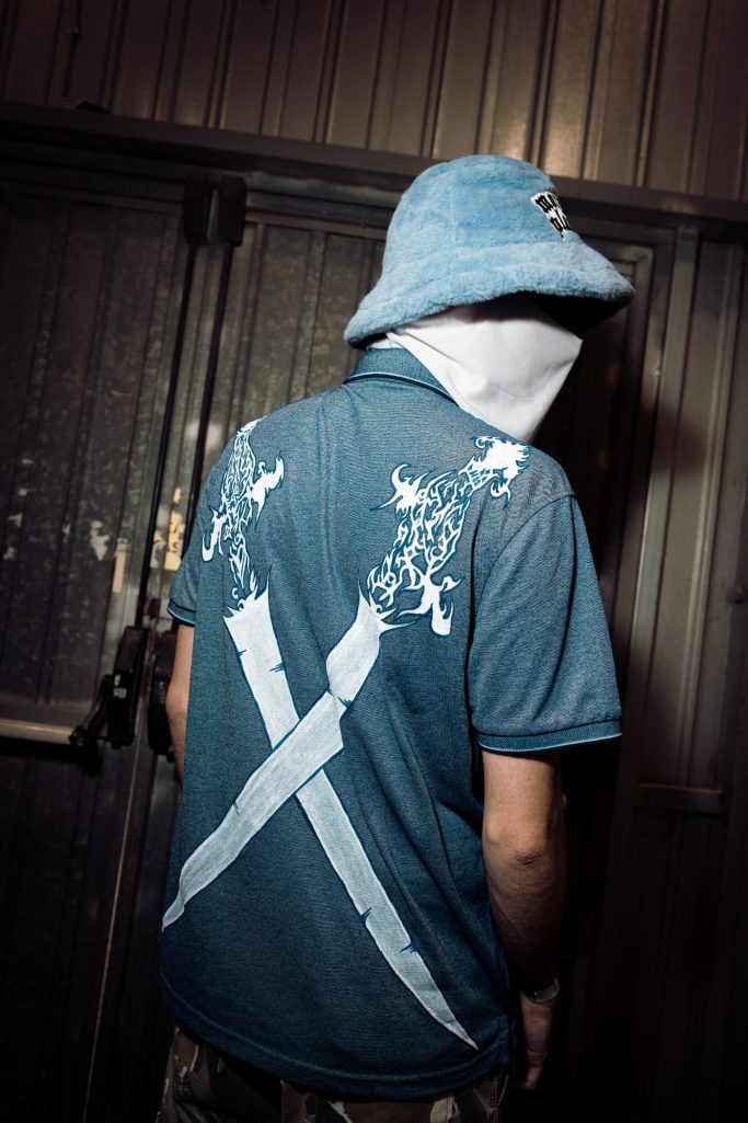 Persona de espaldas, vistiendo una camiseta azul con un diseño de espadas blancas.