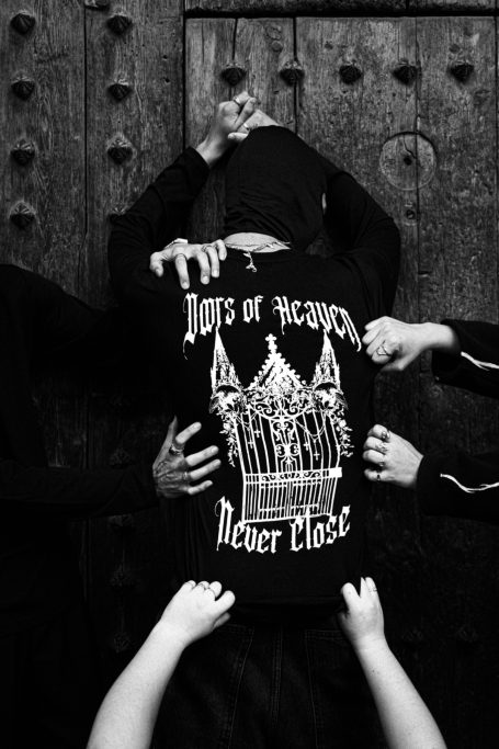 Persona con sudadera negra frente a una puerta, manos que parecen empujarla.