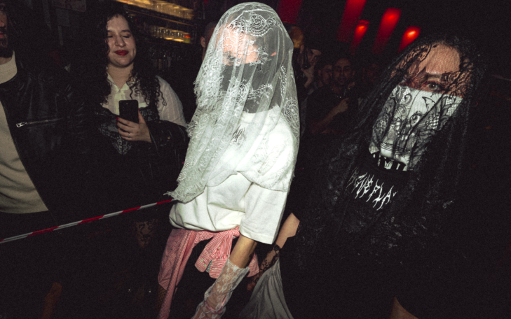 Dos personas con velos, vestidas con camisetas y pantalones, en un ambiente oscuro.