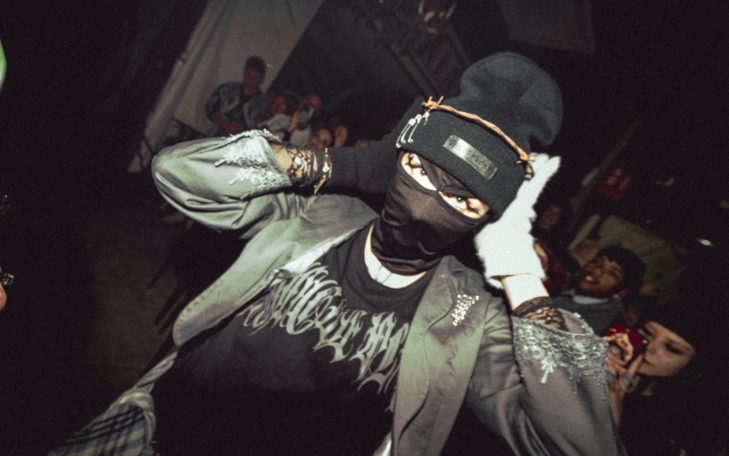 Persona con gorro y máscara negra, en un ambiente festivo.